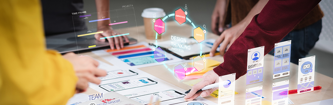 Equip jove d'Andorra col·laborant en un projecte, definint el producte que volen crear amb wireframes d’una app, post-its de colors i diagrama del procés de design thinking.